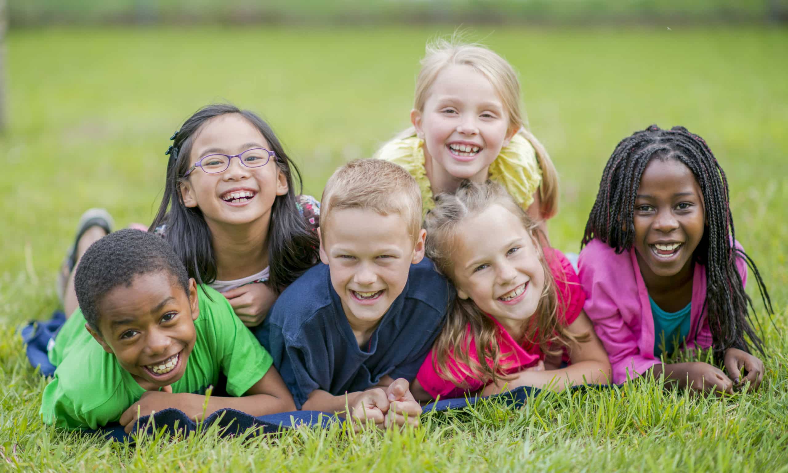 Group of smiling children laying in grass