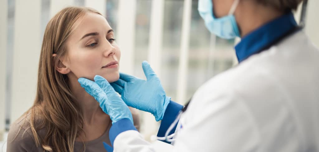 Concept of professional consultation in therapist system. Close up portrait of doctor woman examining tonsils of smiling young lady in medical office