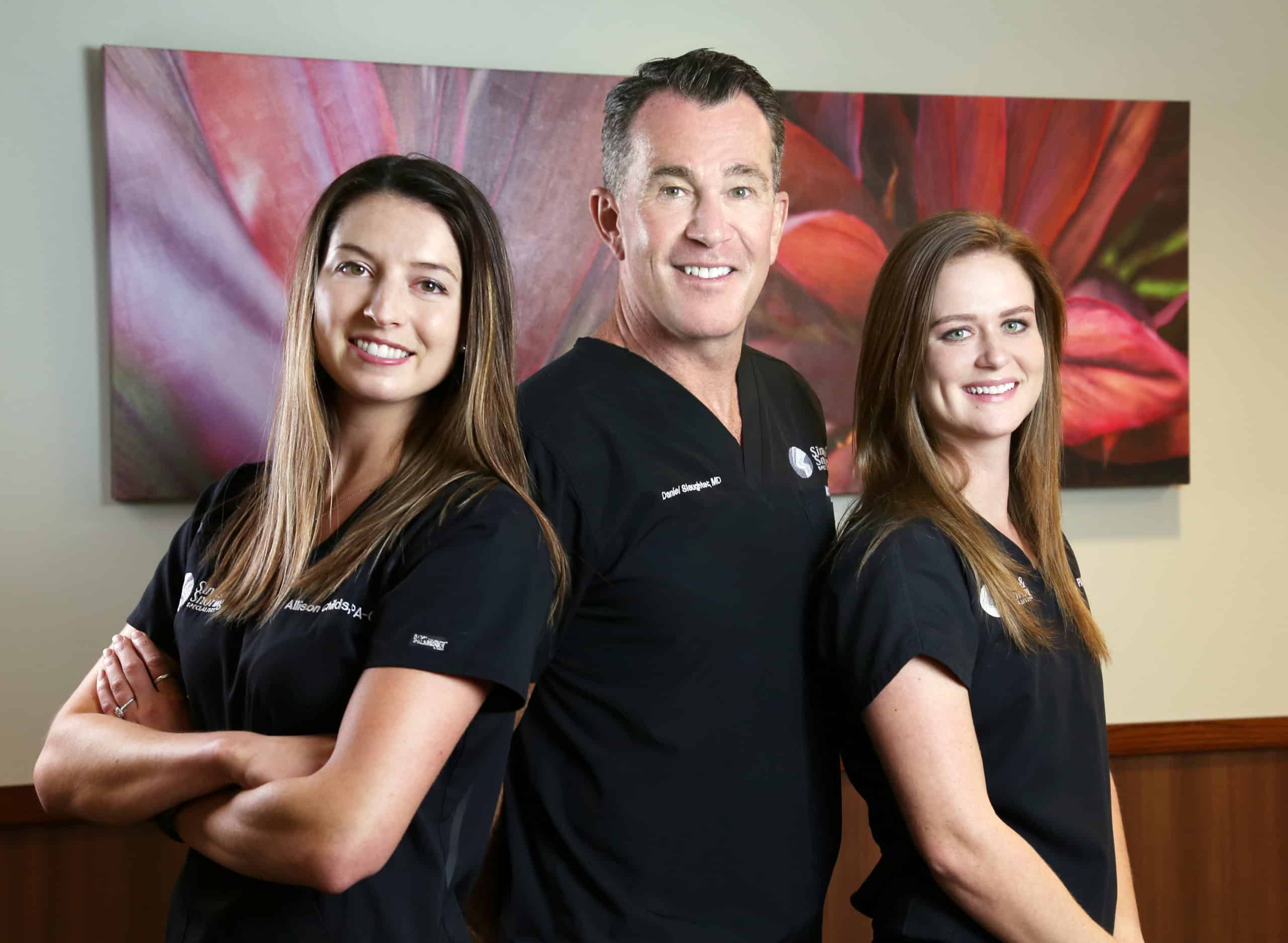 three ENT specialists in company uniform posing together at office