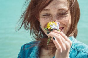 Happy woman smiling and smelling a flower.