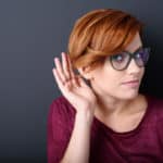 woman with a hearing her hand behind ear