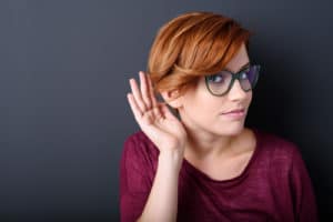 woman with a hearing her hand behind ear