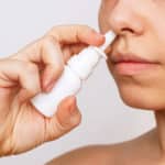 Cropped shot of a young caucasian woman using nasal spray for a runny nose and congestion