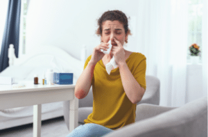 woman sitting on couch while using nasal spray for her runny nose